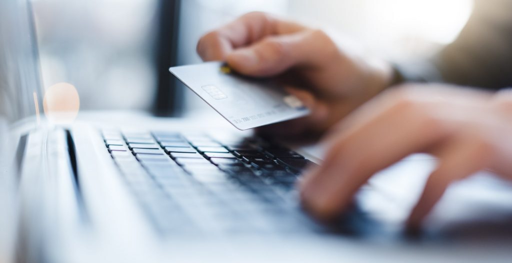 Hands holding credit card over laptop keyboard. 